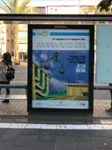 צילום כרזה ליום העברית תשע"ח איור של הכנסת, מנורה, ויד מחזיקה מאזניים וכיתוב "עברית שולטת"